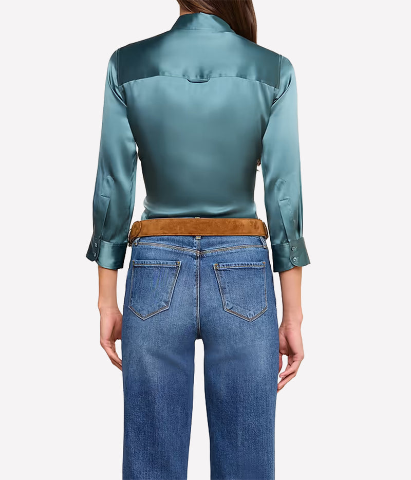 A model shown from the back wearing a cadet blue silk shirt with a brown suede belt and blue jeans.