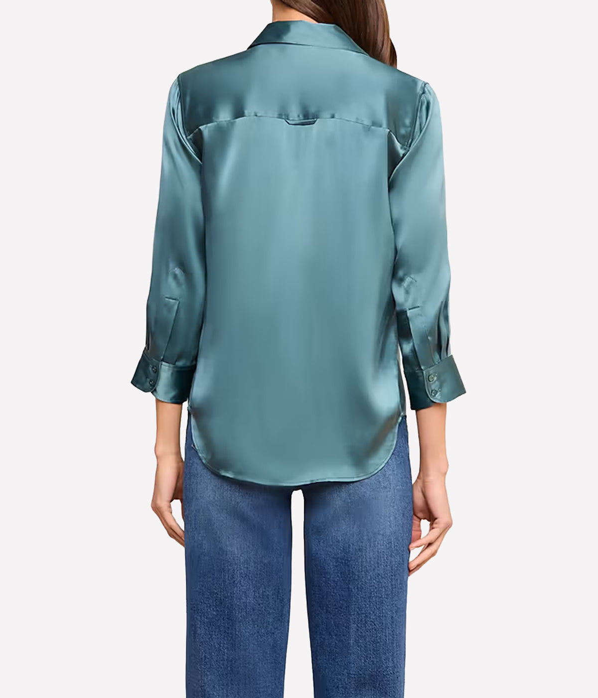 A woman viewed from the back wearing a cadet blue silk blouse with three-quarter sleeves and blue jeans.