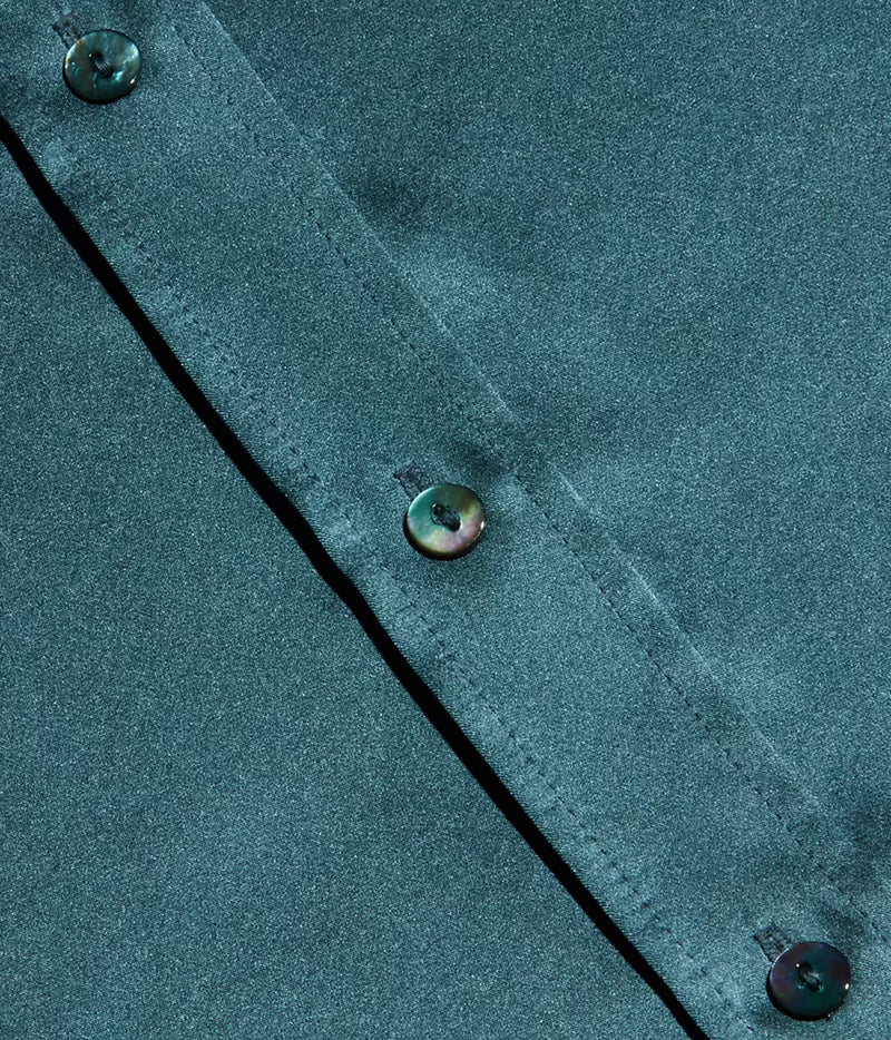 Close-up of a cadet blue silk fabric garment with a diagonal button placket and iridescent buttons.