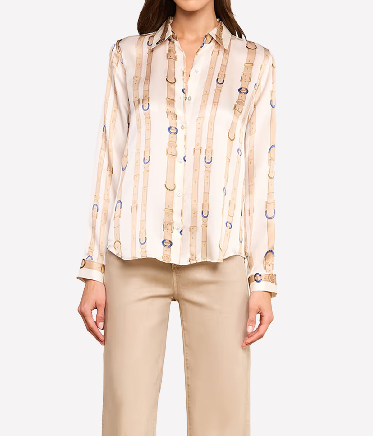 A woman wearing a long-sleeve button-up shirt with a beige and white vertical stripe pattern decorated with gold and blue horsebit motifs, paired with beige trousers.