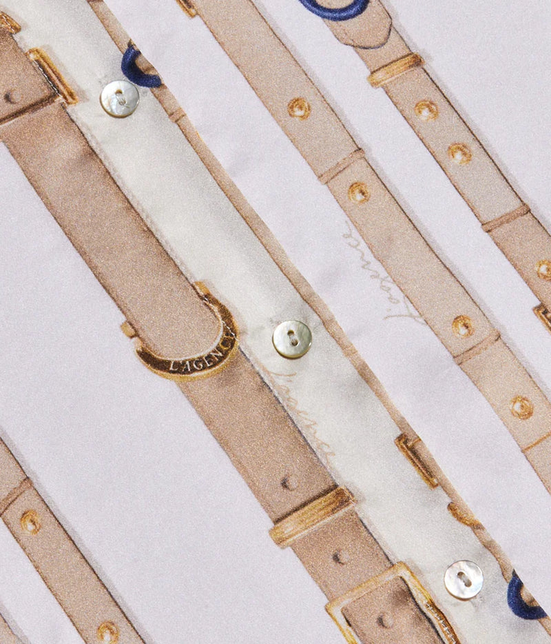 Close-up of a printed shirt fabric featuring a repeating pattern of beige leather-like belts with gold-tone rivets, buckles, and buttons.