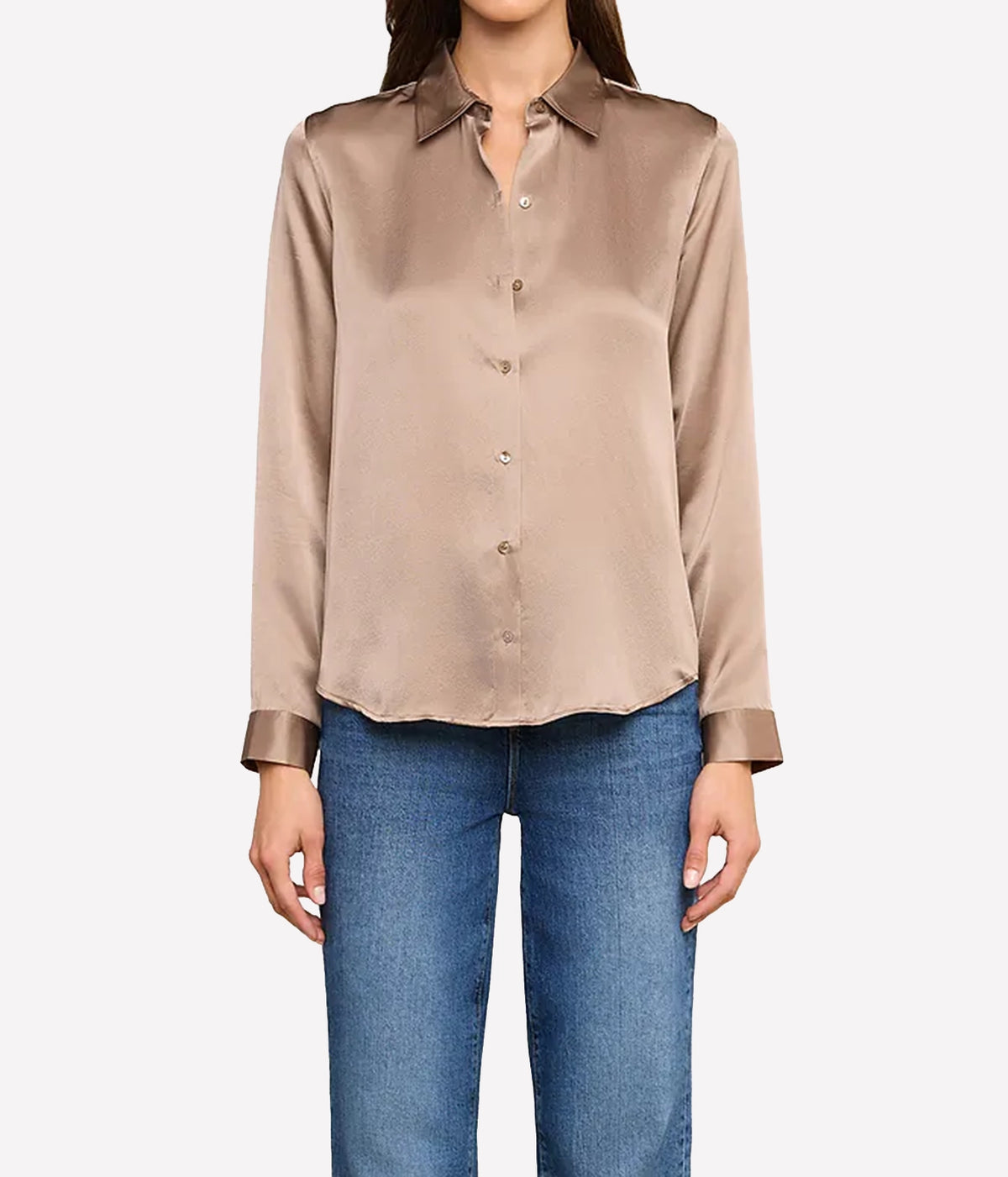 A woman wearing a long-sleeve silk button-up blouse in a taupe-brown colour, paired with blue jeans.