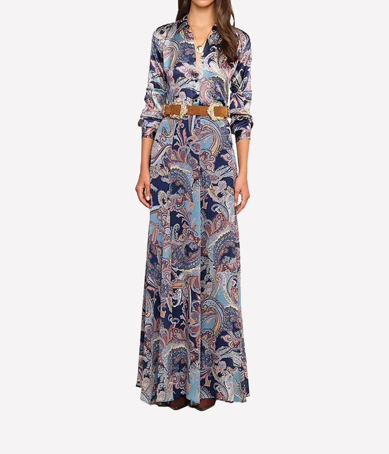 A woman modeling a long-sleeve shirt with a blue, beige, and white paisley pattern, featuring a brown belt at the waist.