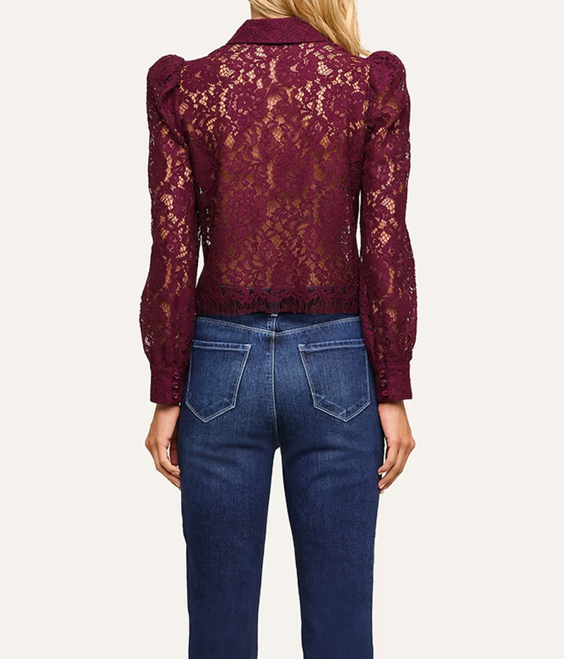 A woman shown from the back wearing a burgundy lace long-sleeve cropped blouse with puffed shoulders and dark blue jeans.
