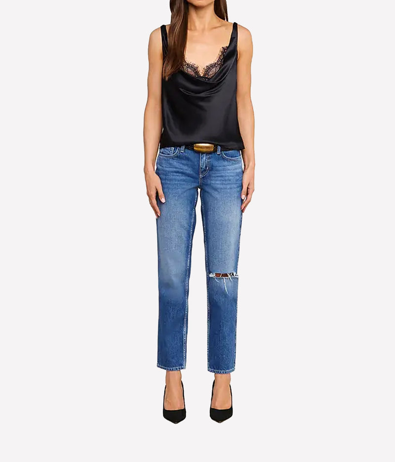 A model wearing the L'AGENCE Evadne Silk Lace Camisole in Black with lace trim, blue jeans, and black pointed-toe heels.