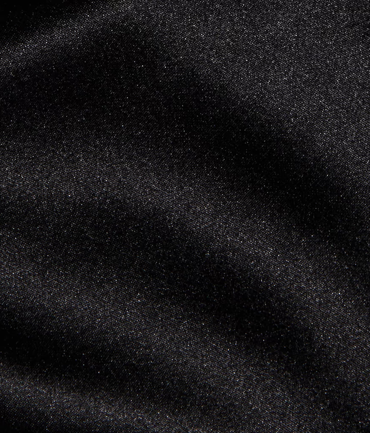 A close-up of the L'AGENCE Evadne Silk Lace Camisole in Black with its silk fabric showing soft folds and shadows. 
