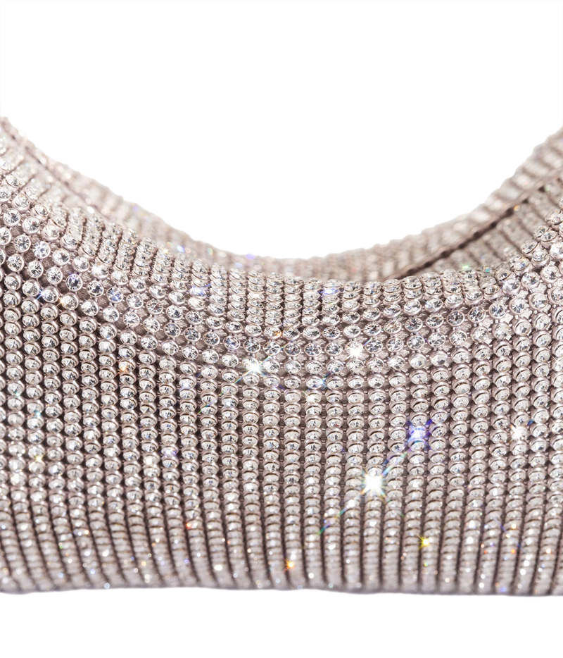 A close-up of a metallic silver rhinestone-covered garment, showing rows of sparkling clear stones on a white background.