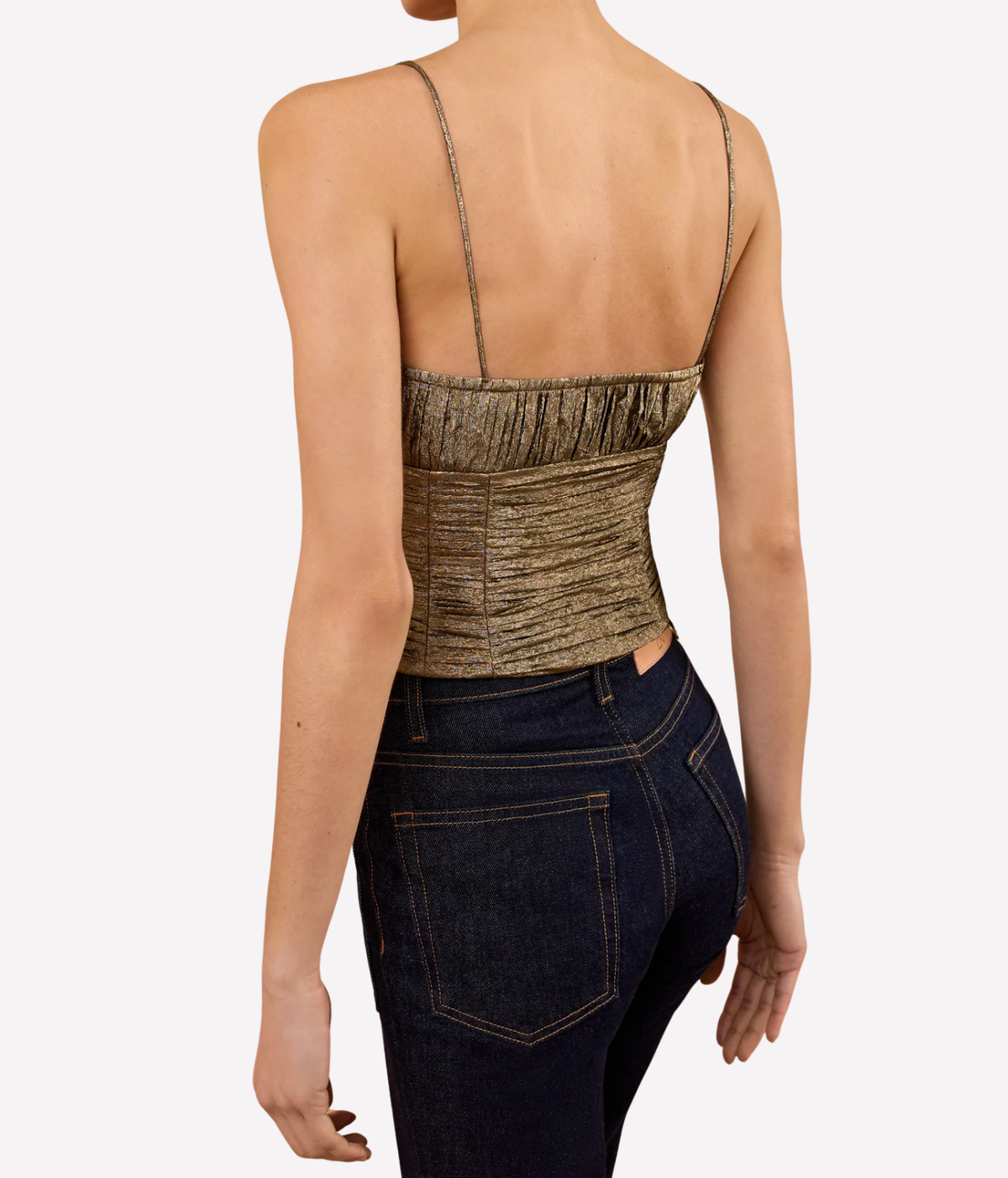 Back view of a model wearing the Ulla Johnson Vina Taffeta Cropped Bustier Top in Light Gold with dark indigo jeans, showing the fine straps and ruched back panel