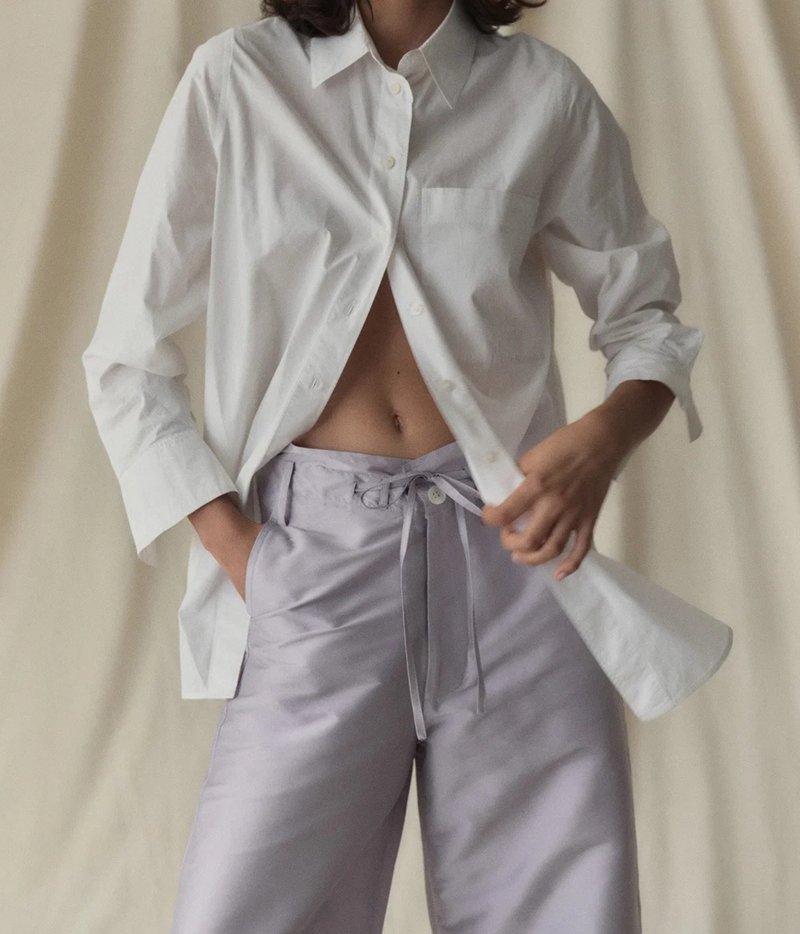 Model wearing the Chan Luu Techno Taffeta Barrel Pant in Lilac with an oversized white button-up shirt worn open with the sleeves pushed up, showing the front waist tie and button closure