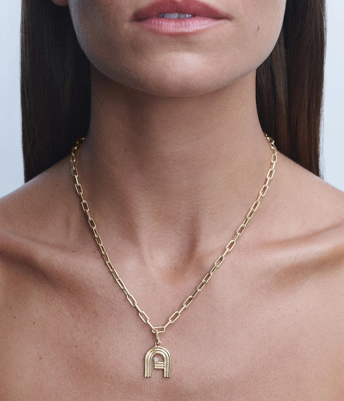 Model wearing the Adina Reyter 4mm Wide 16" Italian Chain Link Necklace in 14K Yellow Gold at the base of the neck with a gold letter charm