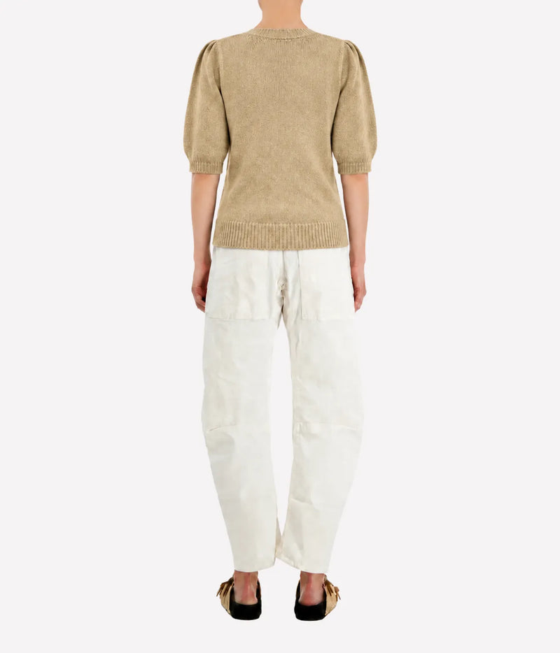 Back view of a model wearing the Avant Toi Cashmere Short Sleeve in Burro with cream barrel-leg trousers and dark sandals, showing the gathered shoulders