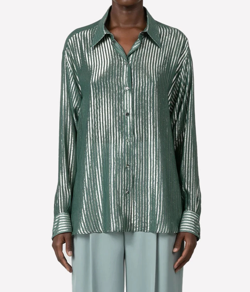 A model wearing a green and white vertically striped long-sleeve button-up shirt tucked into high-waisted, wide-leg light blue trousers, shown against a plain light gray background.