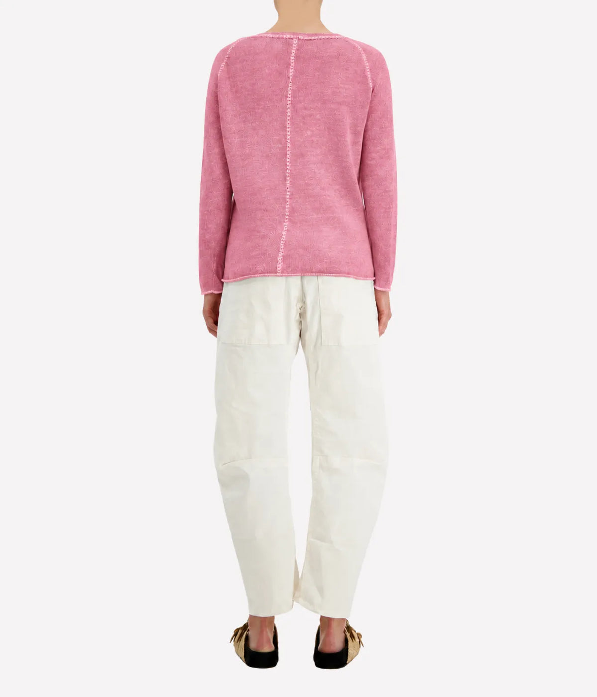 Back view of a model wearing the Avant Toi Maglia Pullover In Rose Skin with cream barrel-leg trousers and dark sandals, showing the contrast centre-back seam
