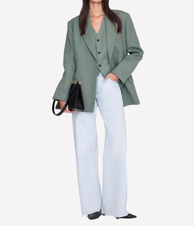 Model wearing the Anine Bing Mario Vest in Sage under a matching sage blazer worn open, with light-wash wide-leg jeans, black pointed shoes