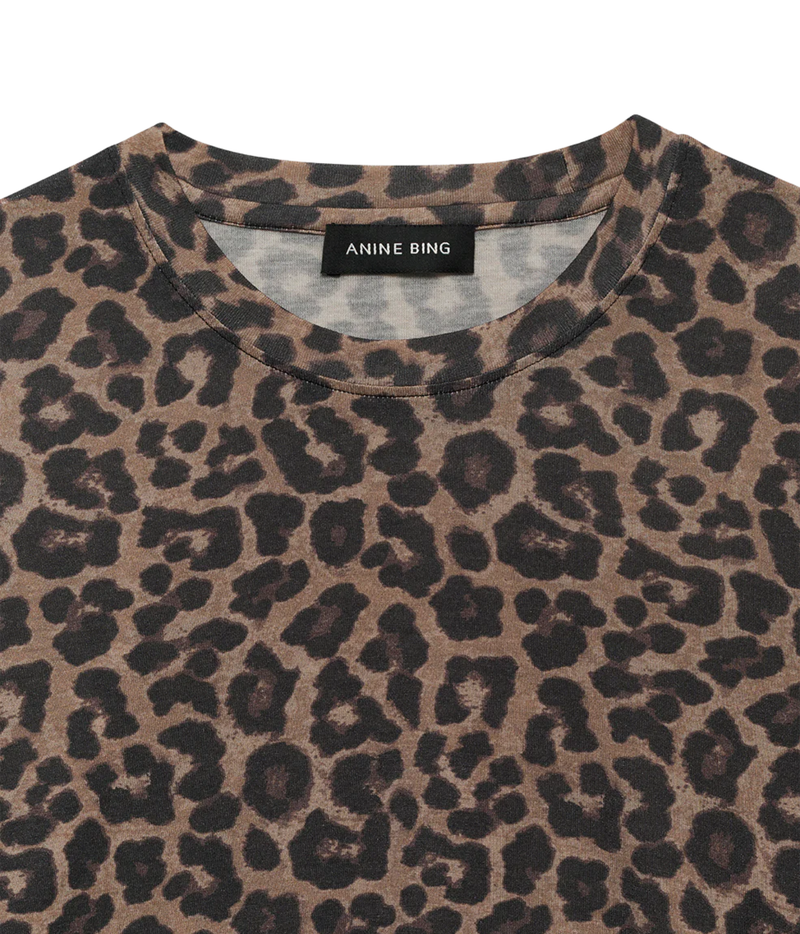 Close-up of a crewneck top with an Anine Bing leopard print pattern in brown and black, featuring a black brand label at the inner collar.