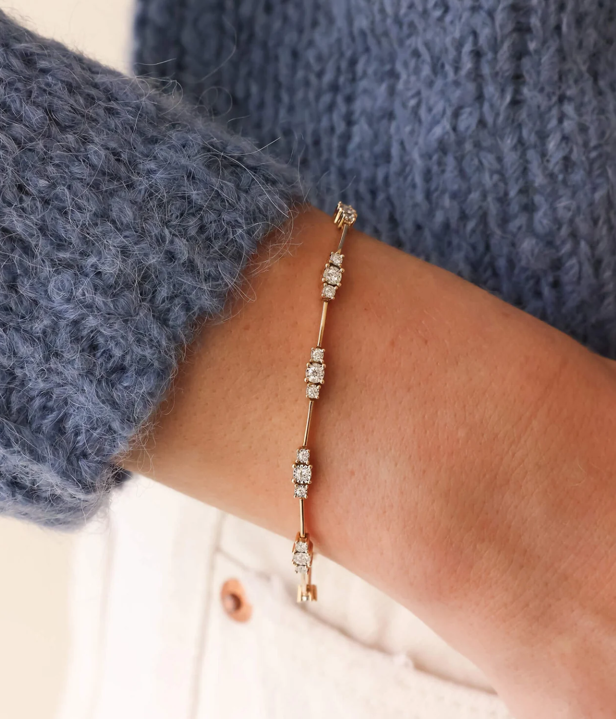 Model wearing the Dana Rebecca Designs Ava Bea Spaced Tennis Bracelet in 14k Yellow Gold on her wrist with the sleeve of a navy knit jumper pushed back