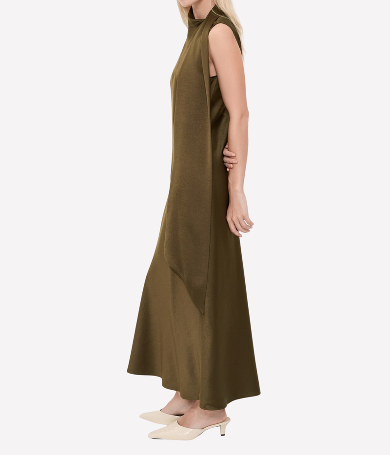 Three-quarter side view of a model wearing the Vince Draped Scarf Tie Dress In Cypress with cream flats