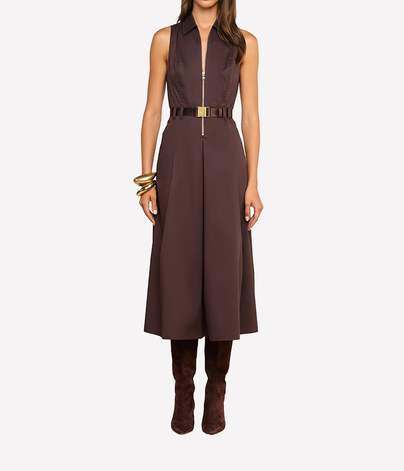 A model wears a sleeveless brown midi dress with a front zipper, a matching brown belt with a gold buckle, and brown boots.