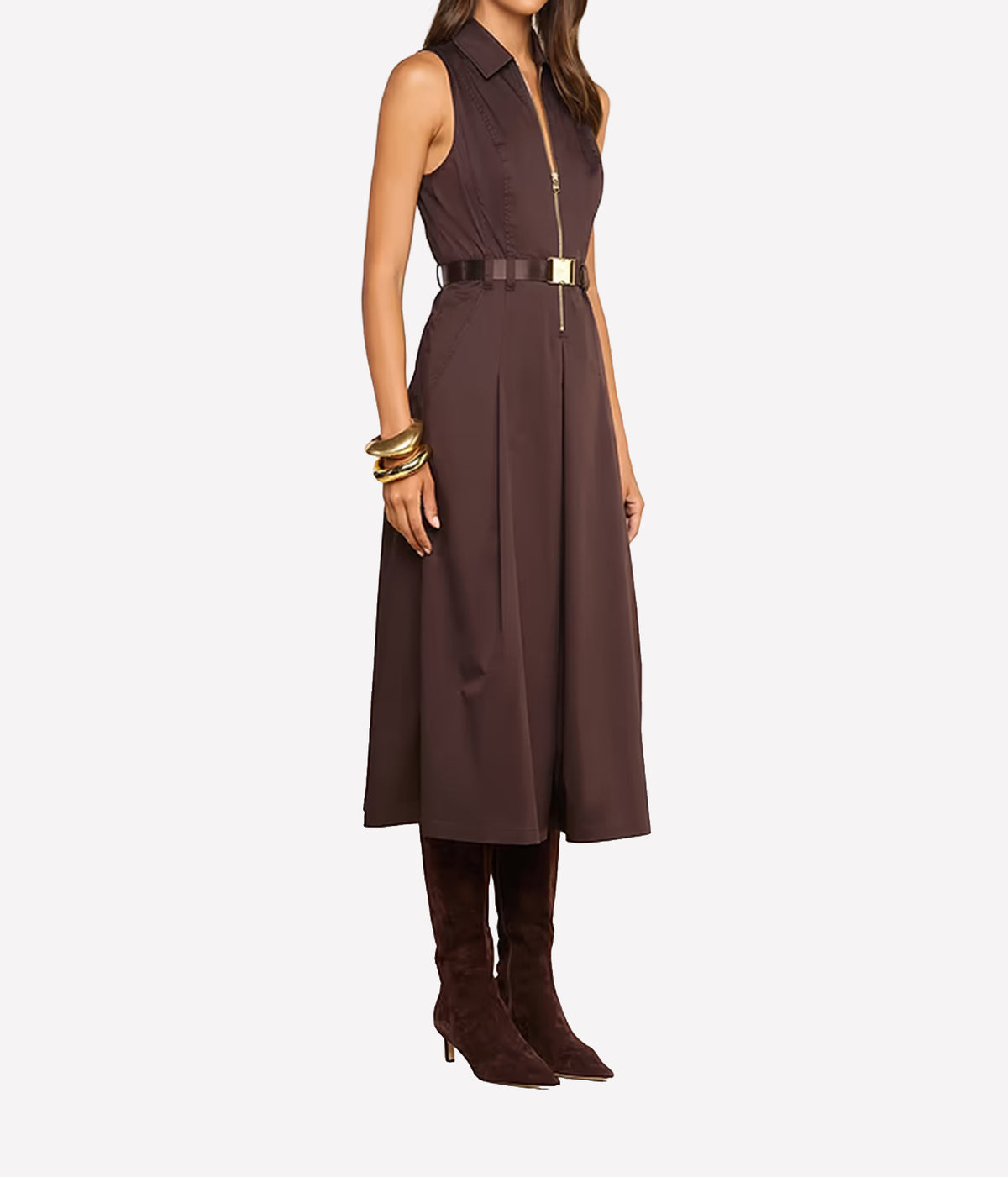 A woman models a sleeveless dark brown midi dress with a front zipper, a matching dark brown belt with a gold-tone buckle, and dark brown knee-high heeled boots.