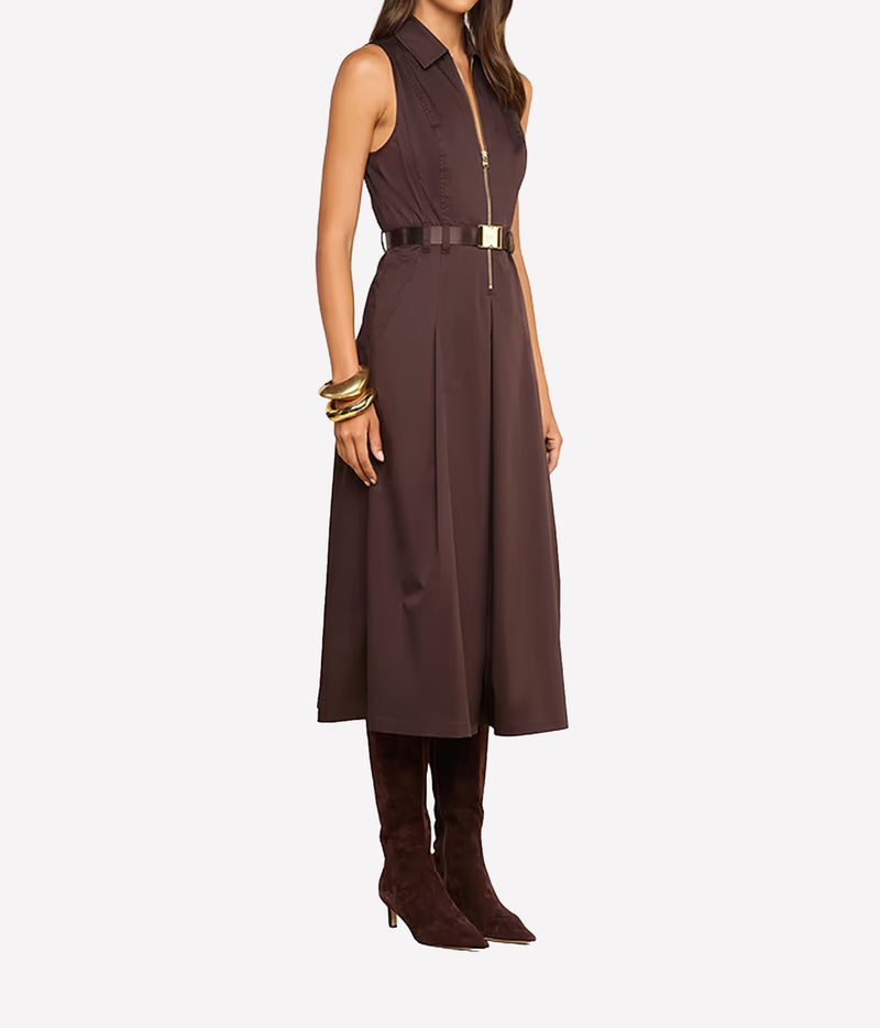 A woman models a sleeveless dark brown midi dress with a front zipper, a matching dark brown belt with a gold-tone buckle, and dark brown knee-high heeled boots.