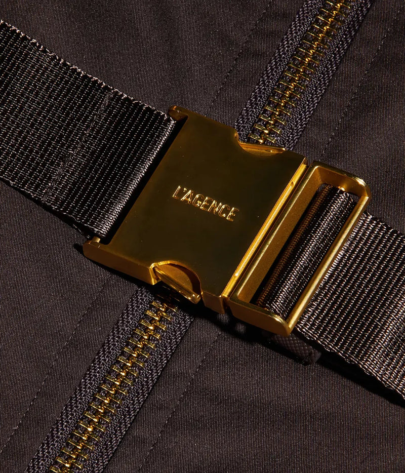 Close-up of the dress featuring a brown belt with a prominent gold-tone metal buckle engraved with the brand name 'L'AGENCE'.