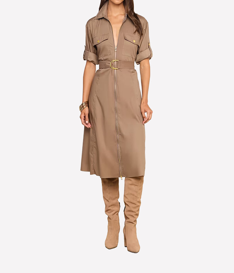 A model wearing a taupe-brown short-sleeve shirt dress with a front zipper, belt, and gold-tone hardware, paired with matching taupe over-the-knee boots, against a light gray background.