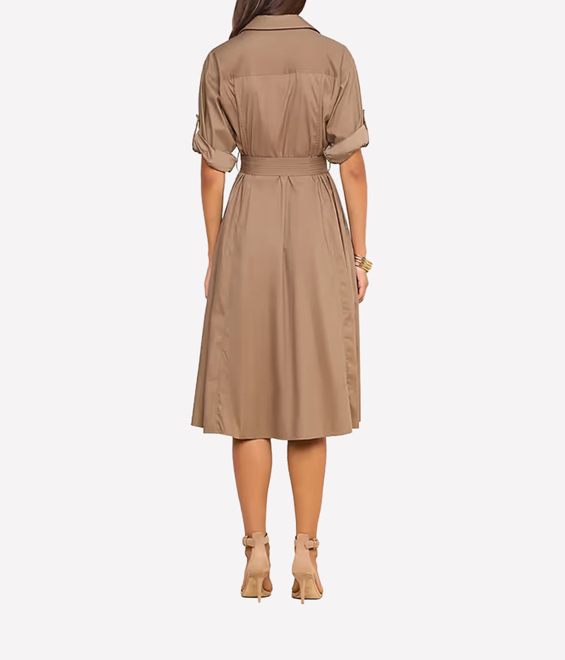 A woman viewed from the back wearing a taupe-brown short-sleeve shirt dress with a matching waist belt, paired with beige ankle-strap heels, against a light grey studio background.