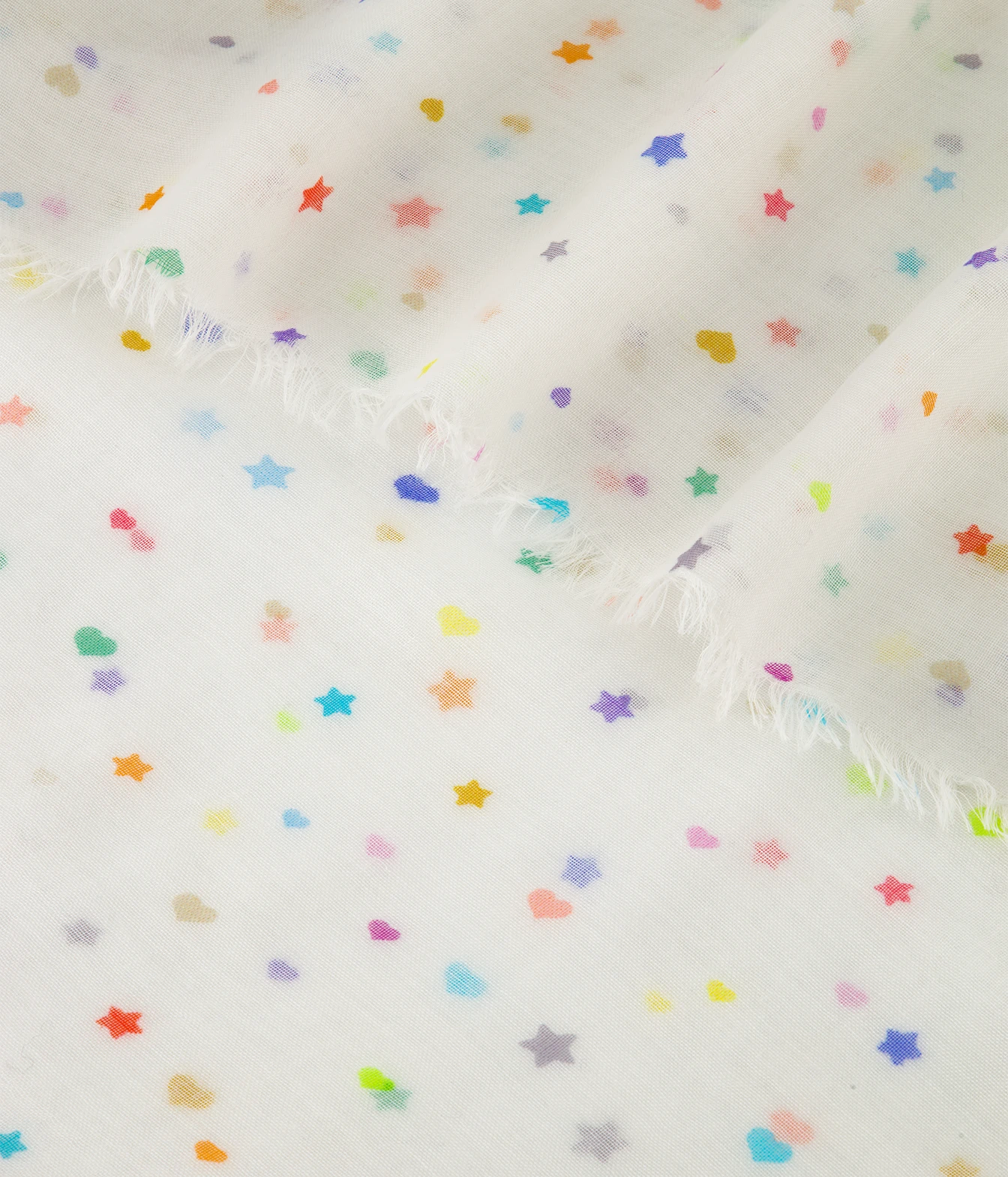 White fabric with a scattered pastel rainbow star and heart pattern and frayed edges.