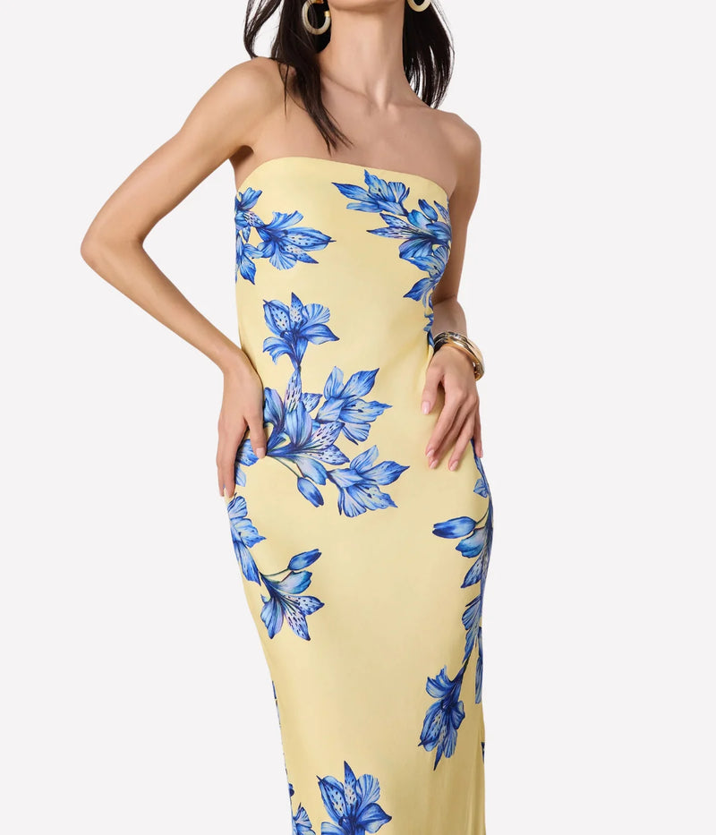 Woman wearing a strapless yellow dress with blue floral patterns on a white background