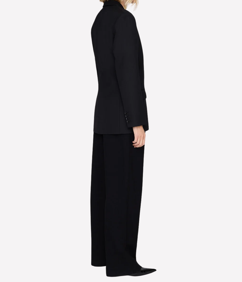 Side profile of a model wearing the Anine Bing Aretha Blazer in Black with black wide-leg trousers and pointed flats, showing the longline length