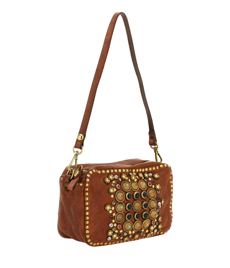 A brown leather shoulder bag with a decorative front panel featuring gold studs, metallic buttons, and small rhinestones, shown against a plain white background.