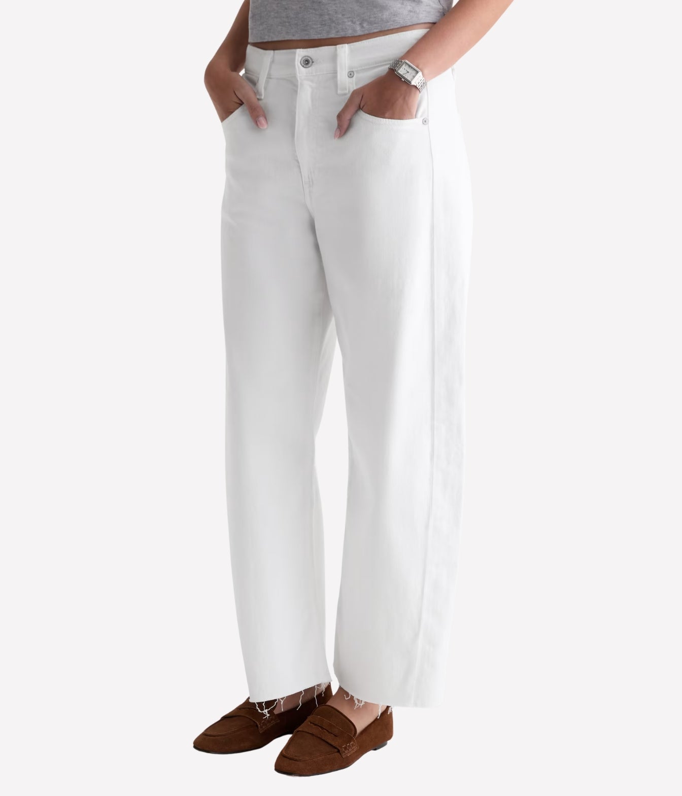 White wide-leg jeans with side pockets, shown on a model from the waist down wearing brown loafers against a light gray background.