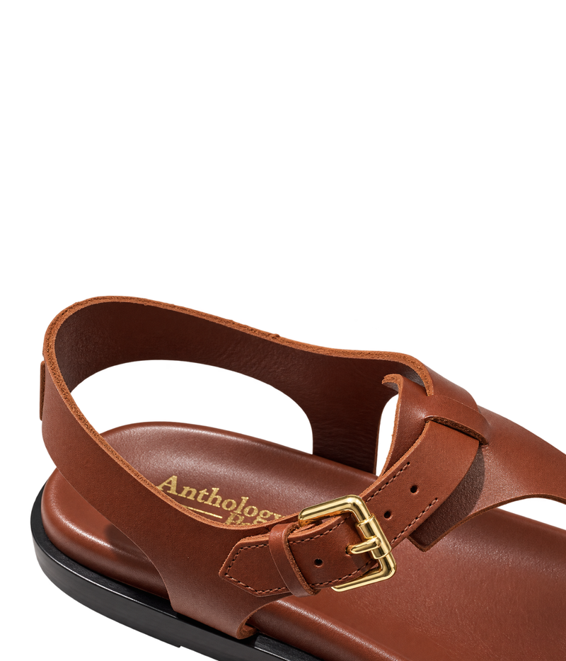 Close-up of a brown leather sandal with a gold buckle and the brand name 'Anthology' printed on the footbed - Anthology Paris Madere Sandal in Tan