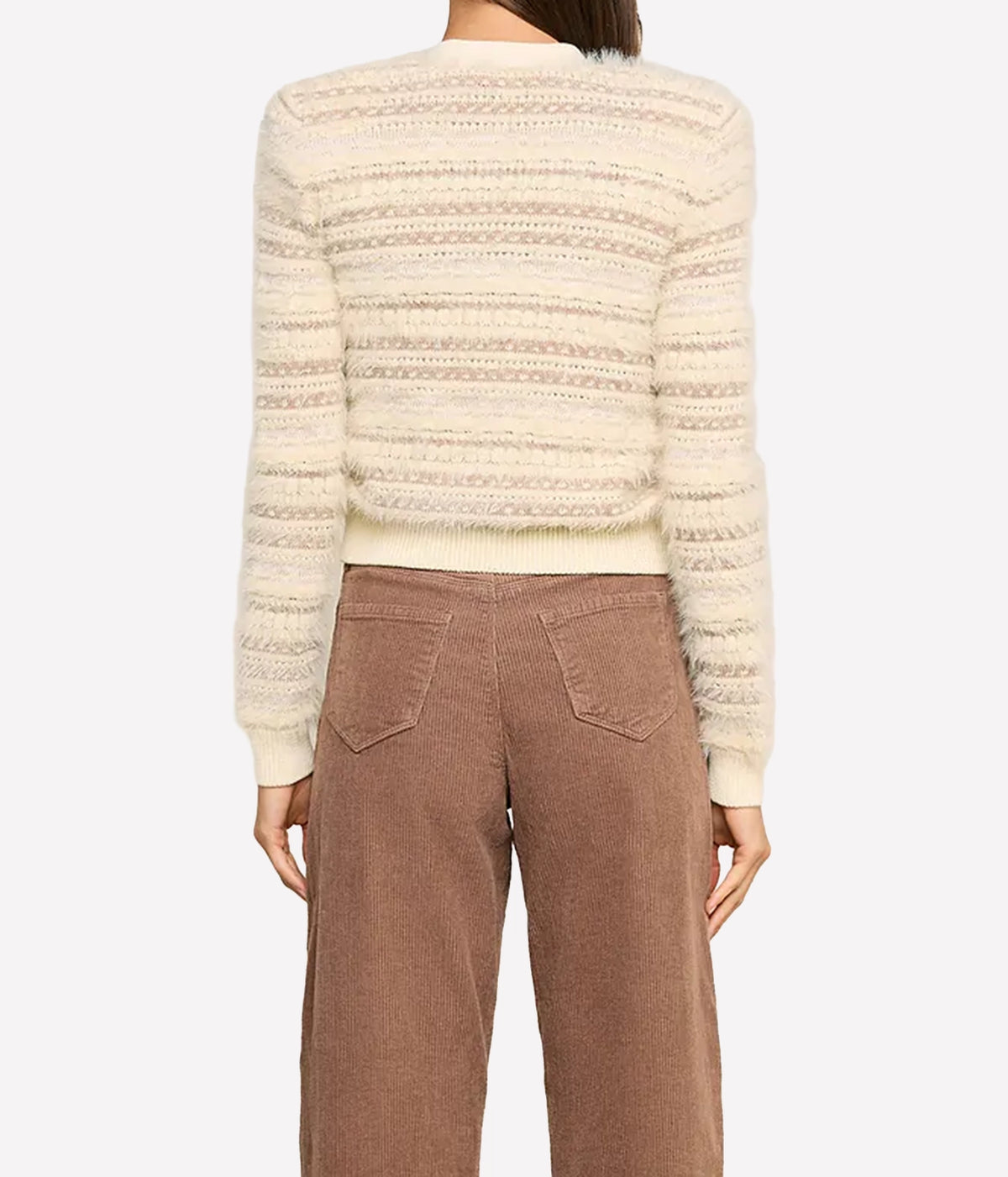 A model wearing a cream-coloured textured knit cardigan with gold buttons and brown corduroy trousers, shot from the back.