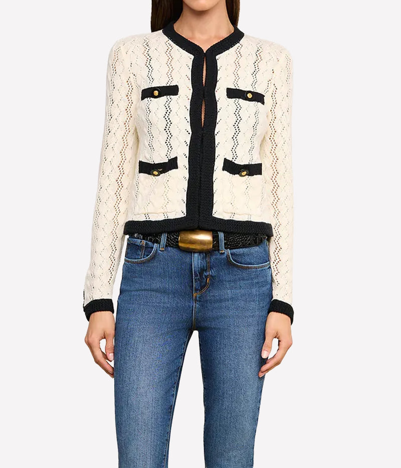 A woman wearing the L'AGENCE Zephyra Pointelle Knit Cardigan in Ivory & Black with black trim and gold-tone buttons, paired with blue jeans and a black belt with a gold buckle.