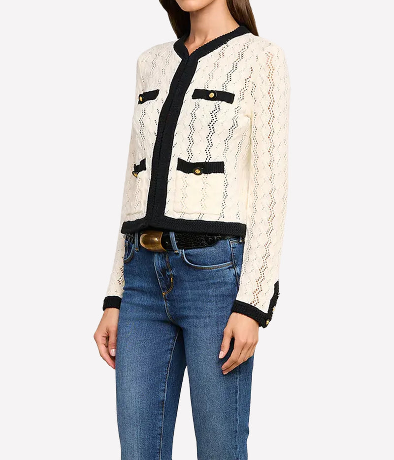 A woman wearing the L'AGENCE Zephyra Pointelle Knit Cardigan in Ivory & Black with black trim and blue jeans.