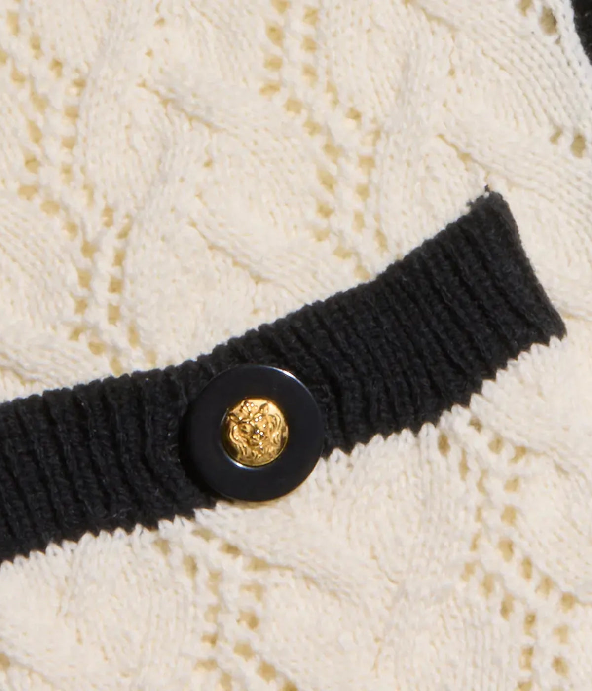 Close-up of the L'AGENCE Zephyra Pointelle Knit Cardigan in Ivory & Black with a black ribbed trim and a black button