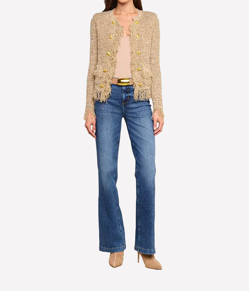 A woman wearing a natural coloured cardigan, a nude top, blue jeans, and beige heels stands facing forward.