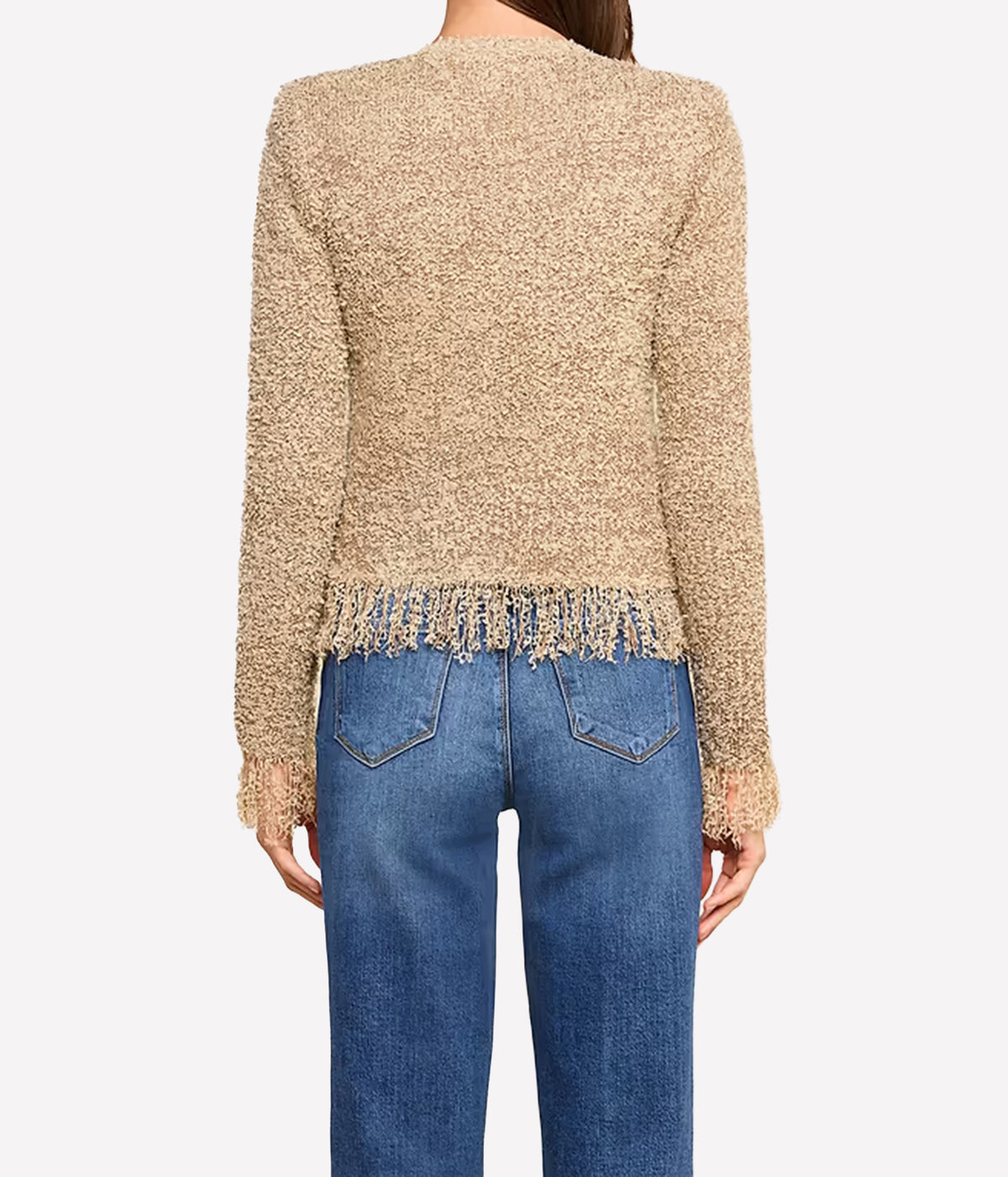 A woman with long brown hair, shot from behind, wears the Mireille Fringe Cardigan, a confetti knit sweater with fringe at the hem, paired with blue jeans.