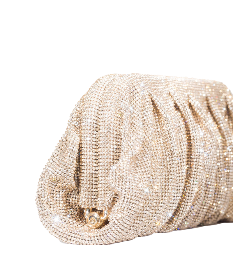 A close-up of a champagne gold rhinestone-embellished clutch purse with a gathered, pleated texture and a small gold clasp, set against a plain white background.
