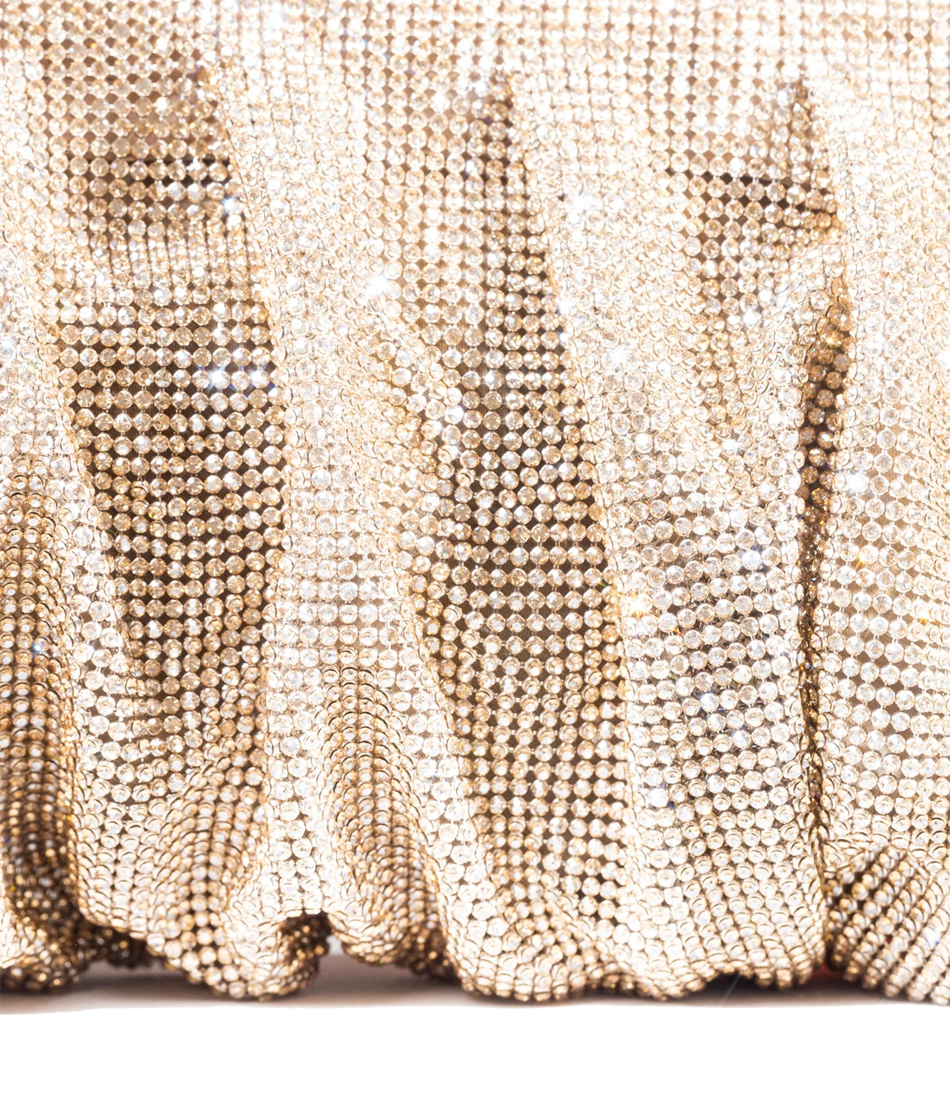 A close-up of a gold rhinestone-covered fabric with a shimmering, textured surface and soft folds.