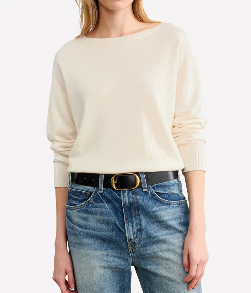Woman wearing a cream sweater and blue jeans with a belt. Nili Lotan Sweater