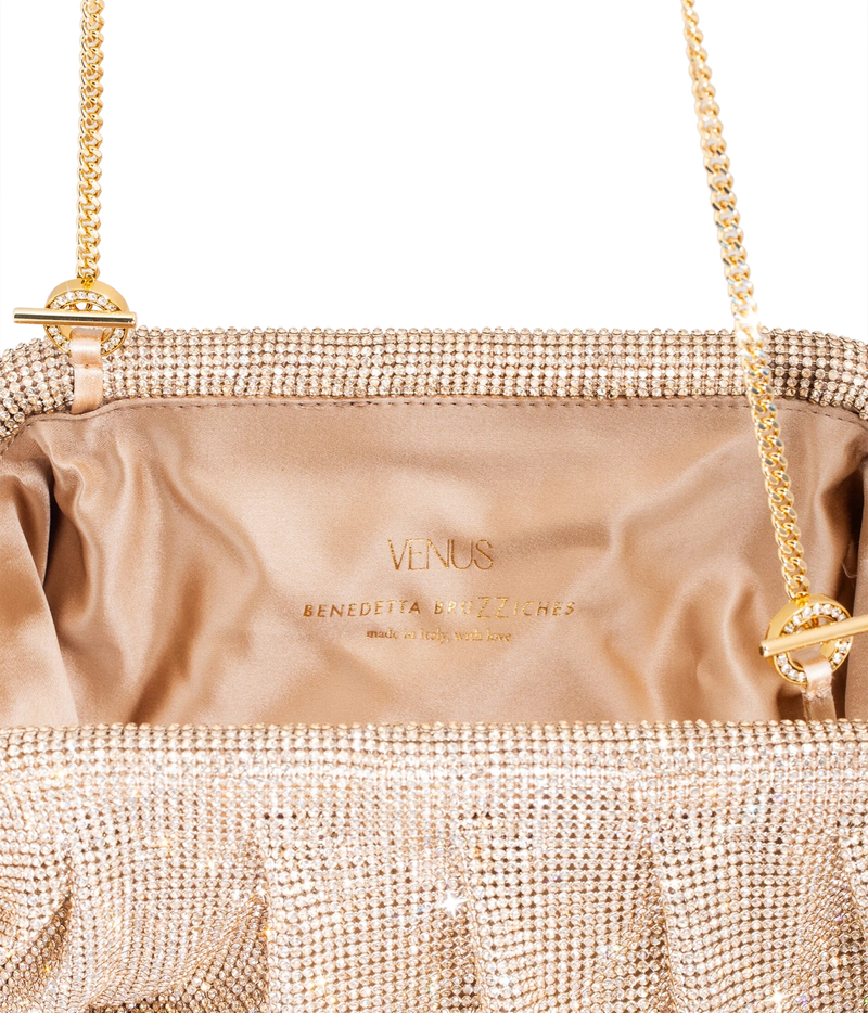 Close-up of a metallic champagne pink rhinestone clutch bag with a satin interior. 