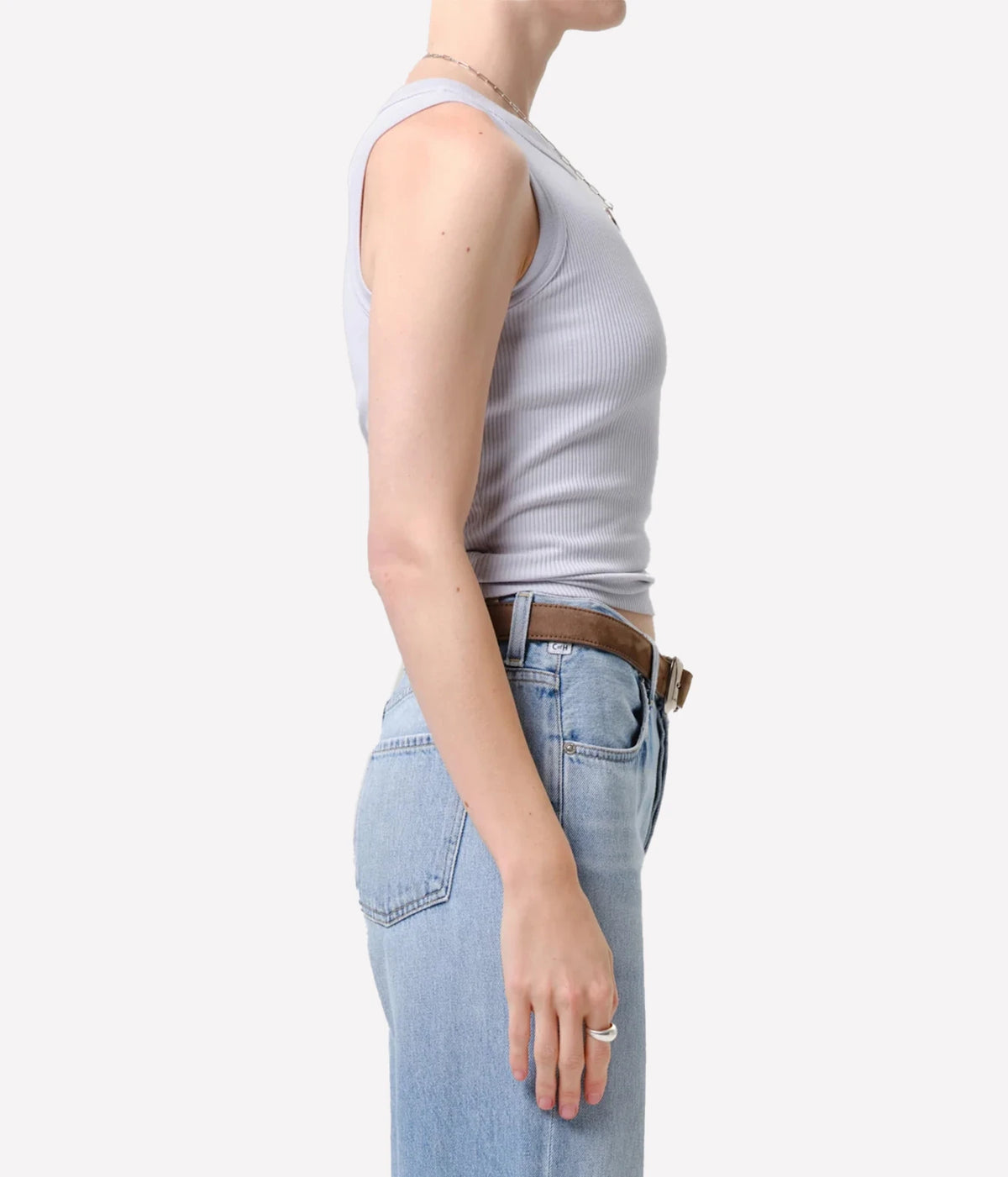 Side profile of a model wearing the Citizens Of Humanity Isabel Rib Tank in Pindary with light-wash jeans and a brown leather belt, showing the fitted ribbed silhouette