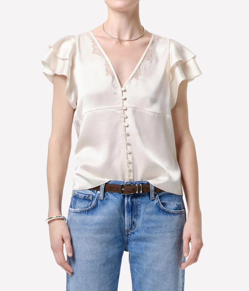 Front view of a model wearing the Citizens Of Humanity Lola Flutter Lace Sleeve Top in Cream buttoned with mid-wash jeans, a brown leather belt and a gold choker necklace