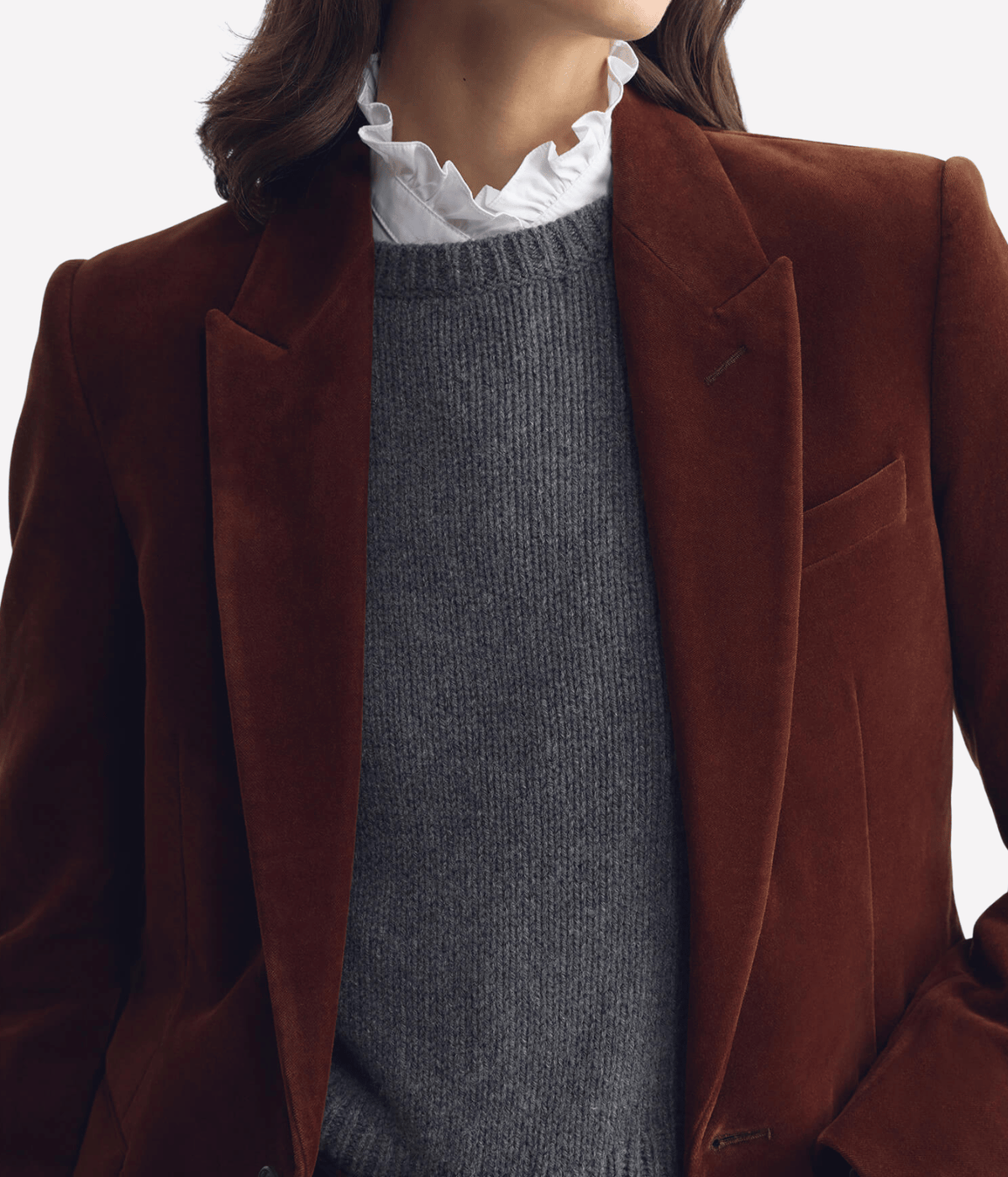 Close-up of a model wearing the Nili Lotan Anabel Tailored Jacket in Burnt Sienna open, showing the lapels and structured shoulders over a charcoal knit and white ruffled collar