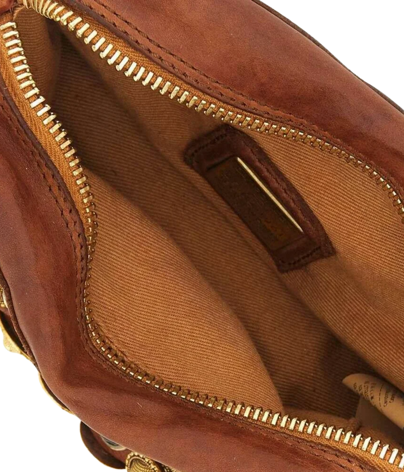 Close-up of the interior of a brown leather bag, showing a tan fabric lining, gold-tone zipper, and a small brown leather brand patch.