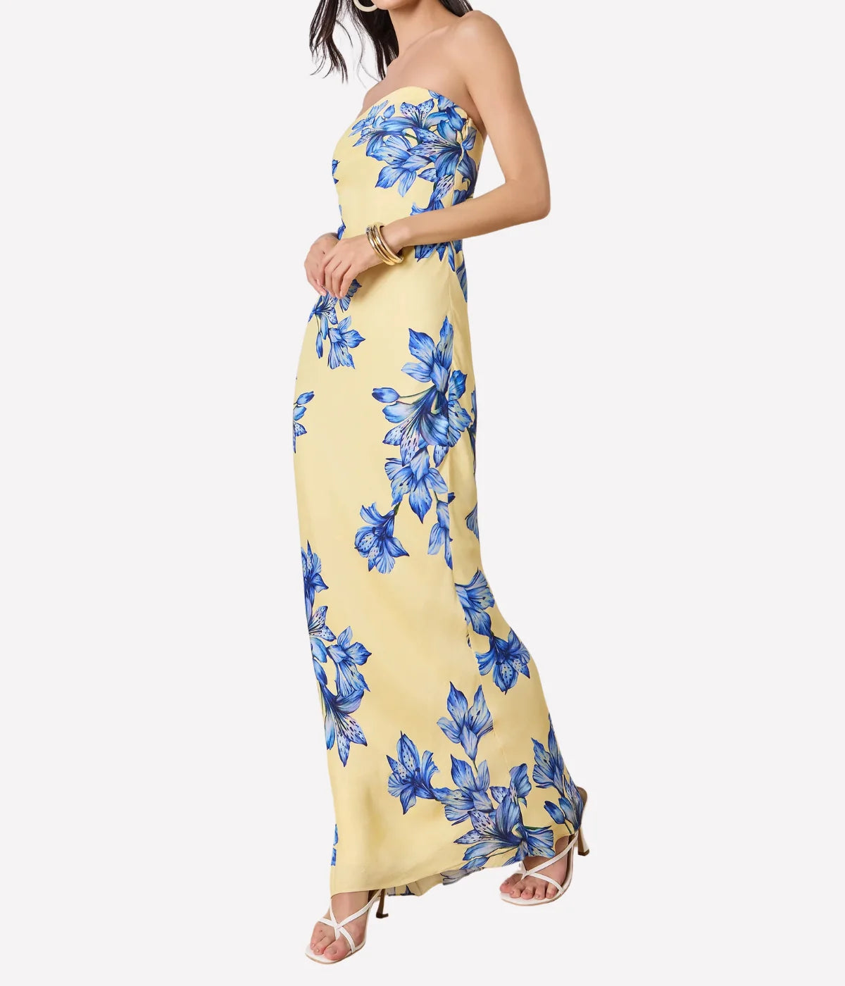 Woman wearing a yellow strapless dress with blue floral patterns on a white background