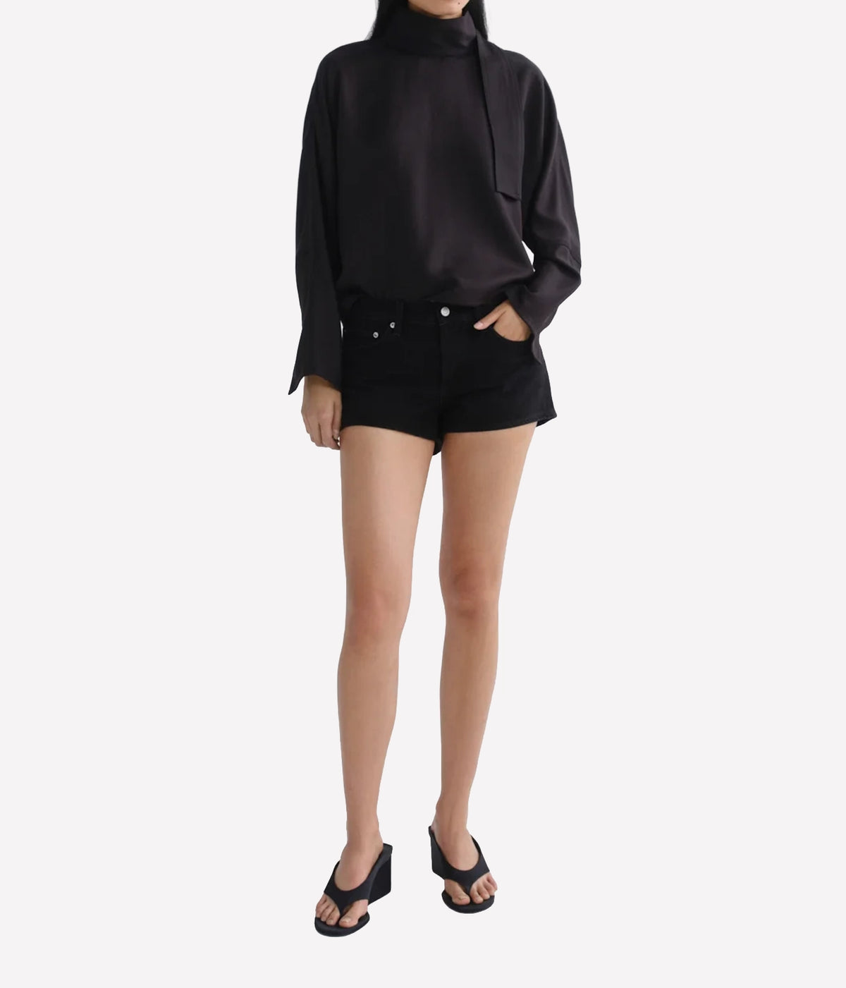 Model wearing the Agolde Low Rise Parker Short in Phase with a black long sleeve and black heeled sandals