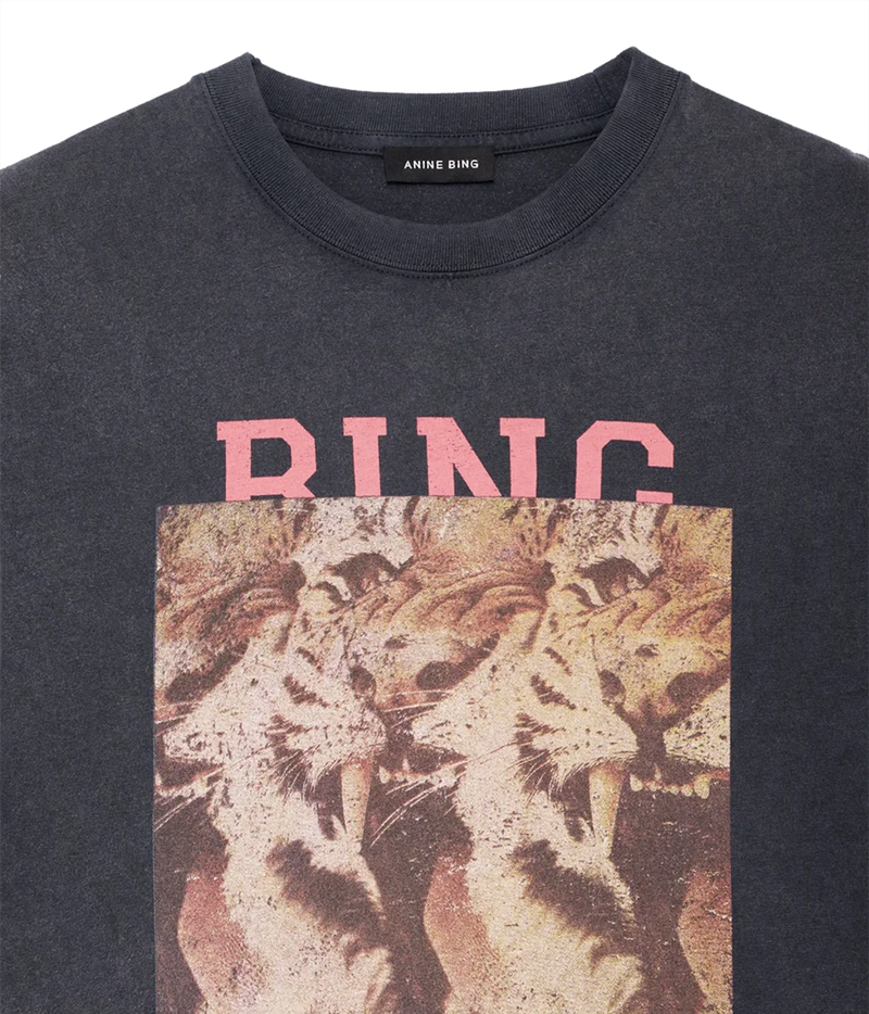 Close-up of a dark charcoal gray t-shirt featuring a pink 'RING' text graphic and a distressed vintage-style print of roaring lions on the front, with the brand name 'ANINE BING' visible on the inner neck label.